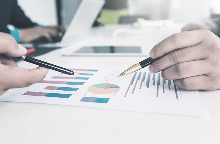 Image cropping with hands and pens analyzing graphs.