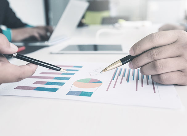 Image cropping with hands and pens analyzing graphs.