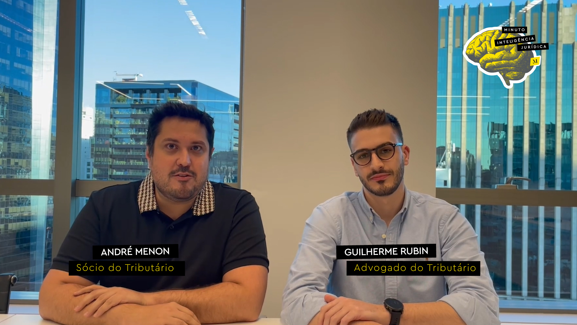 Dois homens, lado a lado, olhando para a foto. O do lado esquerdo tem cabelo preto e curto, barba e usa camiseta preta com colarinho quadriculado. O do lado direito,  tem cabelo preto, barba, óculos de grau preto, e usa camisa social azul. No canto inferior esquerdo, frase com os dizeres "André Menon - sócio do Tributário". No canto inferior direito, frase com os dizeres "Guilherme Rubin - advogado do Tributário". No canto superior direito, logotipo do Inteligência Jurídica