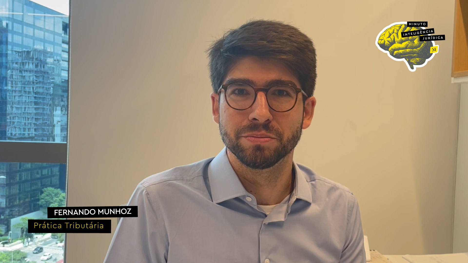 Homem olhando para a foto, com cabelo preto, usando camisa azul e óculos de grau. No canto inferior esquerdo, frase com os dizeres "Fernando Munhoz - sócio do Tributário". No canto superior direito, logotipo do Inteligência Jurídica
