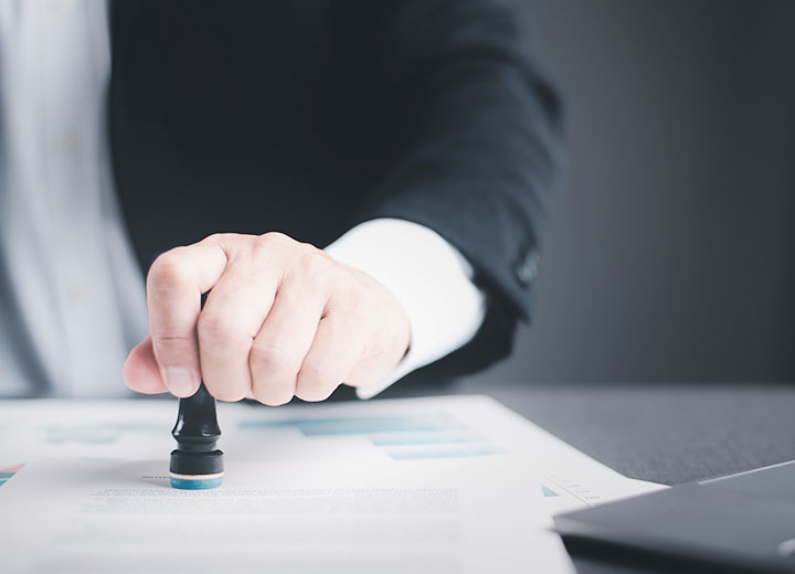 Business person stamp on the contract documents on the desk, the concept of contract confirmation or approval, the authority to authorize solicitation.