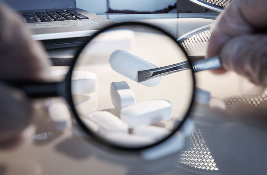 Lupa focando em capsulas de remédio na cor branca