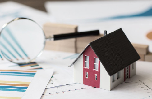 Illustration of a white house with a red stripe between the windows and a black roof. Next to it, magnifying glass and A4 sheets of paper with printed graphics
