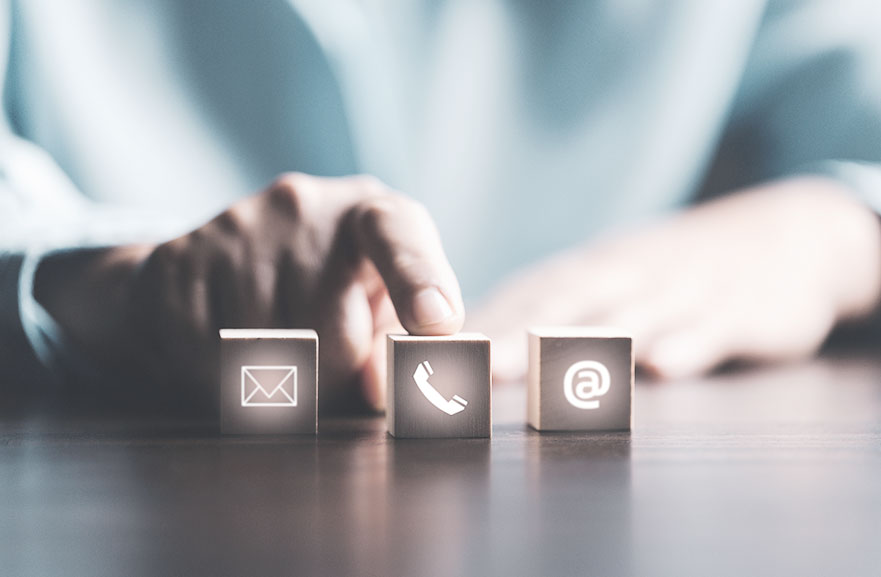 Blocos de madeira 3d com desenhos iluminados representando meios de contato como e-mail, telefone e redes sociais.