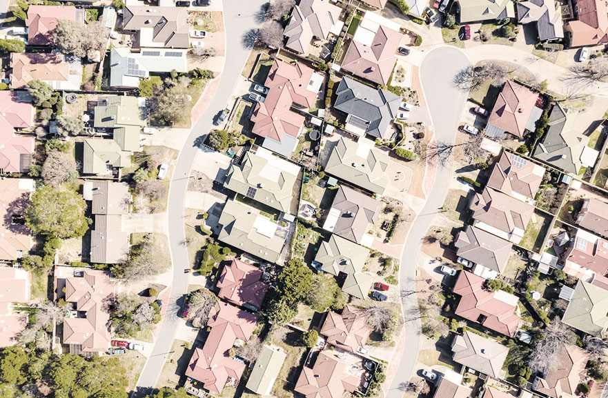 Visão superior de uma vila com várias casas, arbustos e ruas