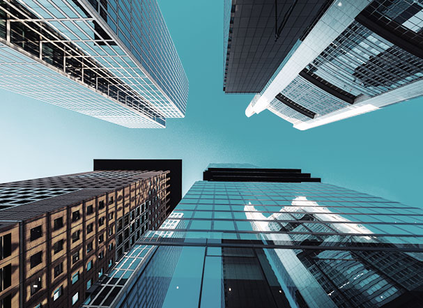 Visão inferior de cinco prédios espelhados, com cores diferentes e posicionados um ao lado do outro