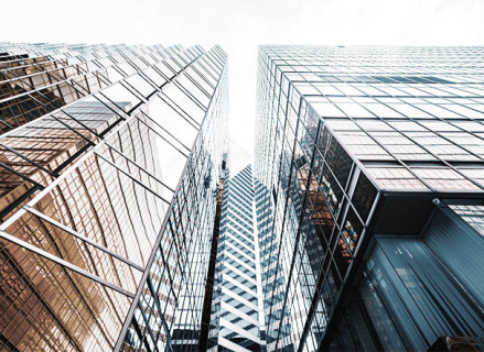 Bottom view of two buildings with mirrored windows, positioned sideways to each other