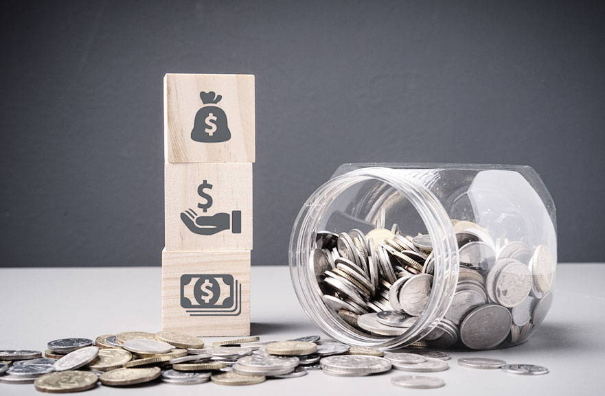 Pote transparente de moedas ao lado de três cubos 3d de madeira