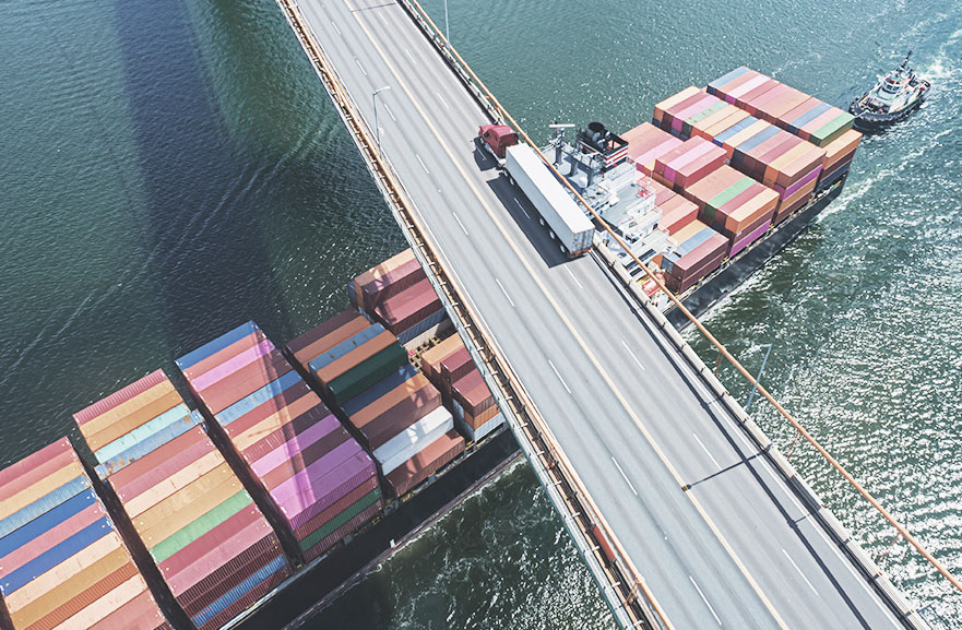 Visão superior de Navio cargueiro passando abaixo de uma ponte