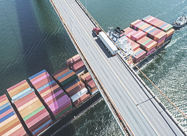 Visão superior de Navio cargueiro passando abaixo de uma ponte
