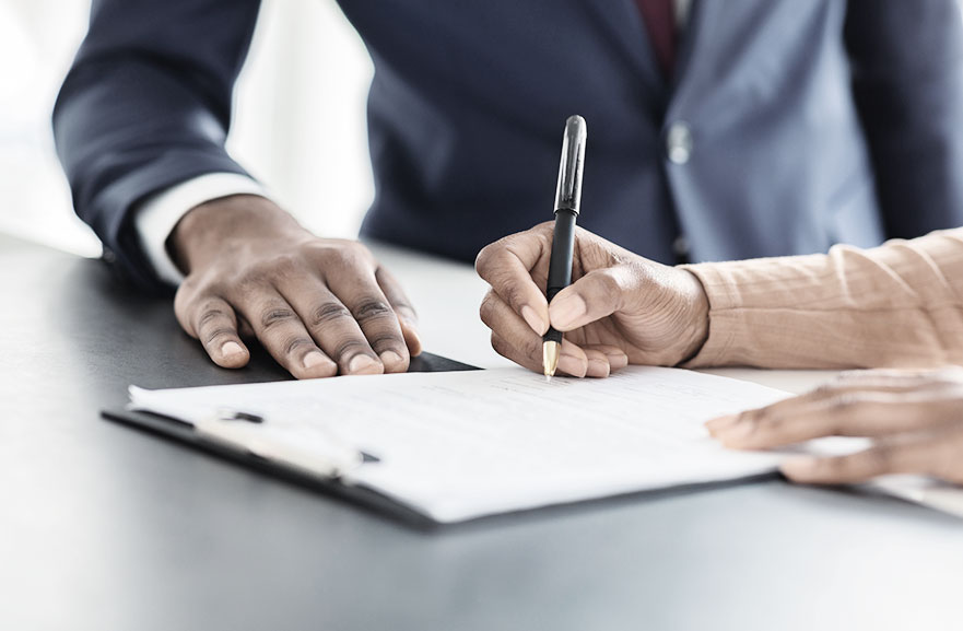 Visão lateral de duas pessoas assinando um documento