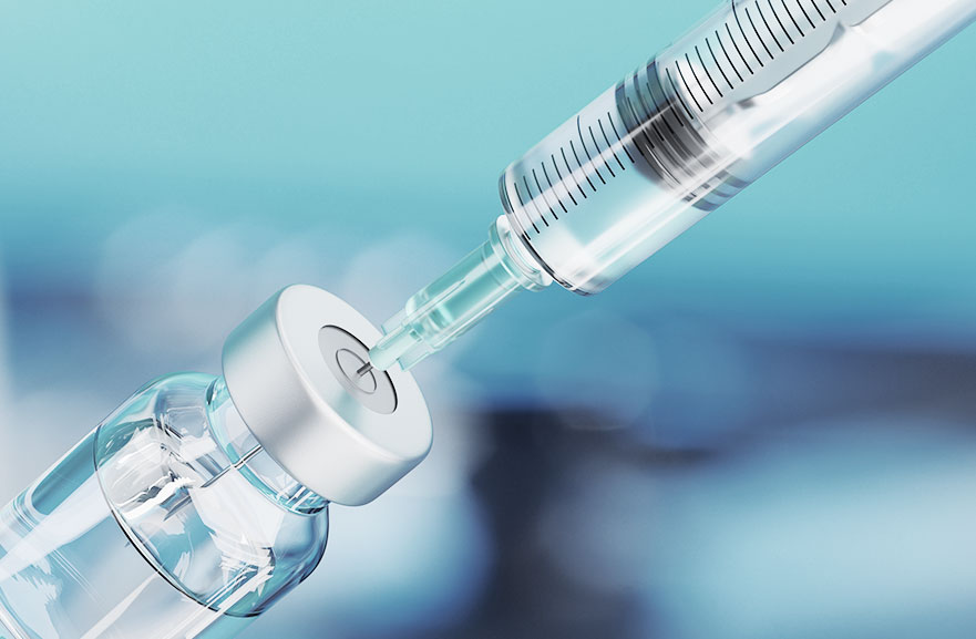 Ampola com líquido ao lado de uma seringa transparente