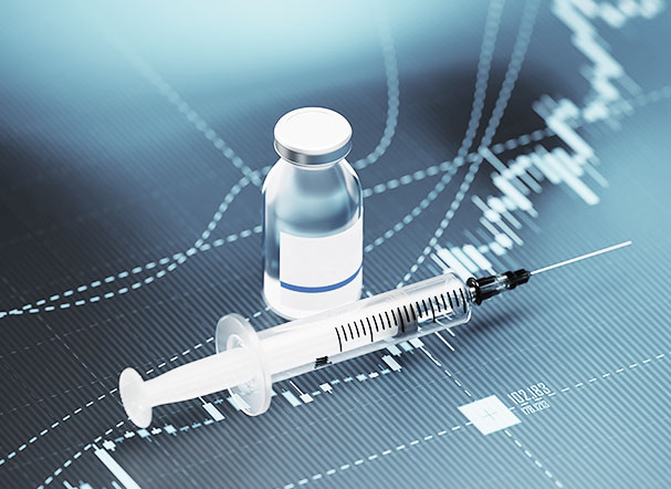 Ampola transparente de vidro com substância liquida, ao lado de uma seringa plástica transparente