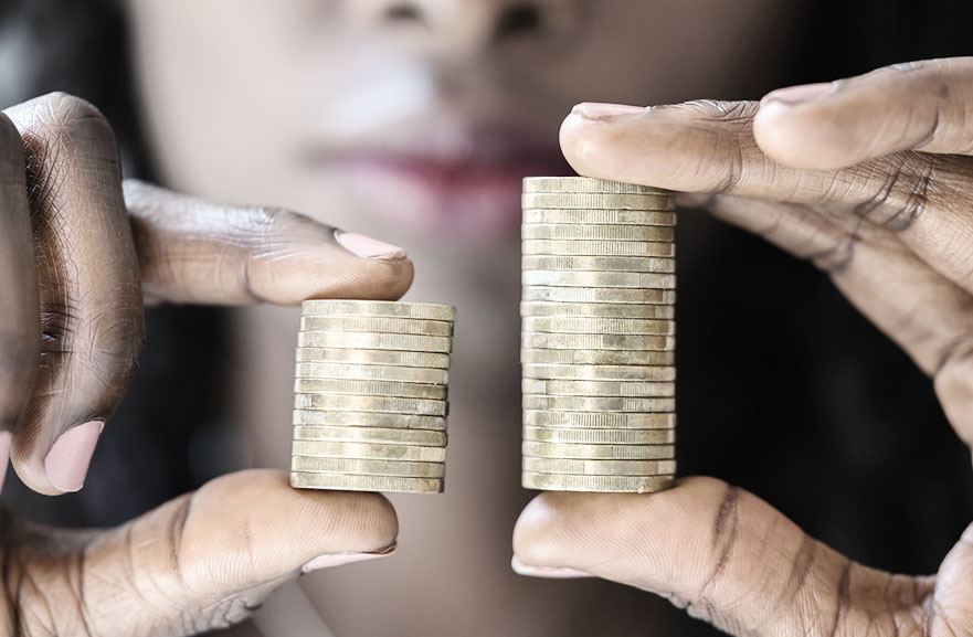 Black woman holding two piles of coins. In her left hand, the coins are fewer in number, while in her right hand, they are greater in number