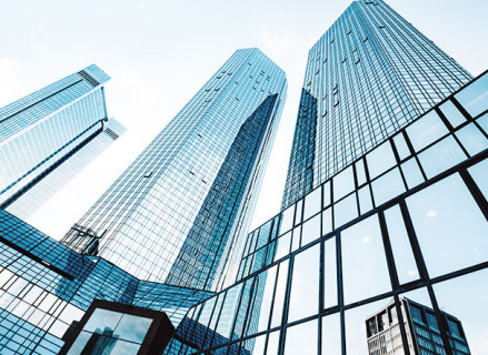 Lower view of several buildings with mirrored structures in blue. The buildings have different structural shapes