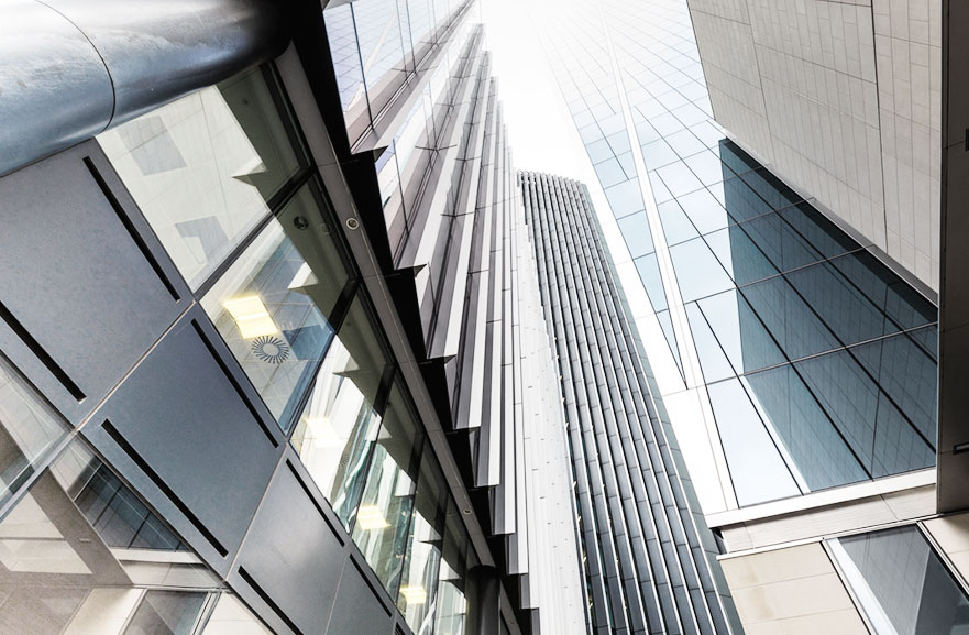 Visão inferior de edifício com janelas espelhadas e estruturas de metal