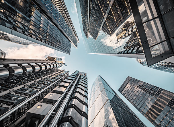 Visão inferior de conjunto de prédios espelhados, num centro urbano.