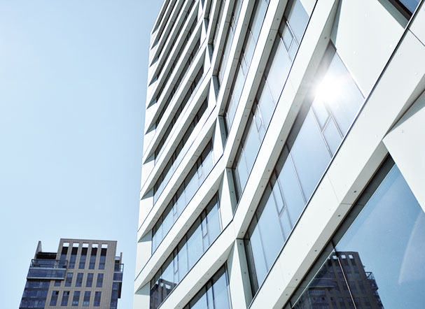 Bottom view of building with white walls and mirrored glass windows