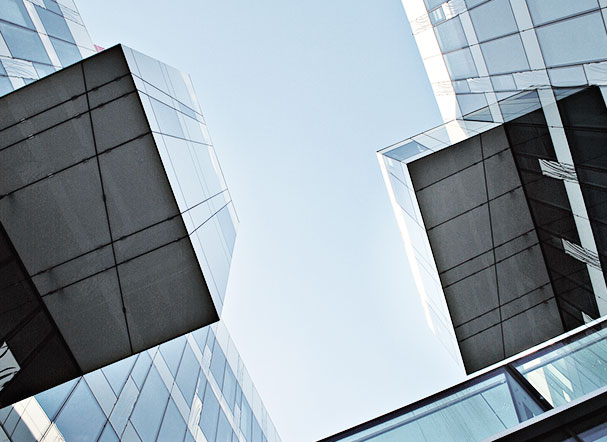 Lower view of two mirrored buildings, one facing the other.