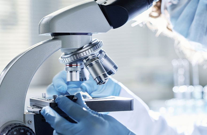 Pessoa utilizando microscópio dentro de laboratório