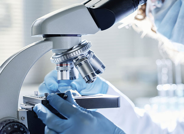 Pessoa utilizando microscópio dentro de laboratório