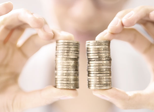 Person holding two equal stacks of gold coins