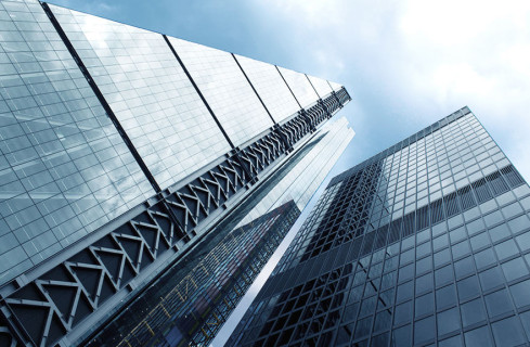 Visão inferior de prédio espelhado com estrutura metálica