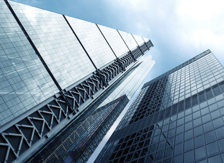 Visão inferior de prédio espelhado com estrutura metálica