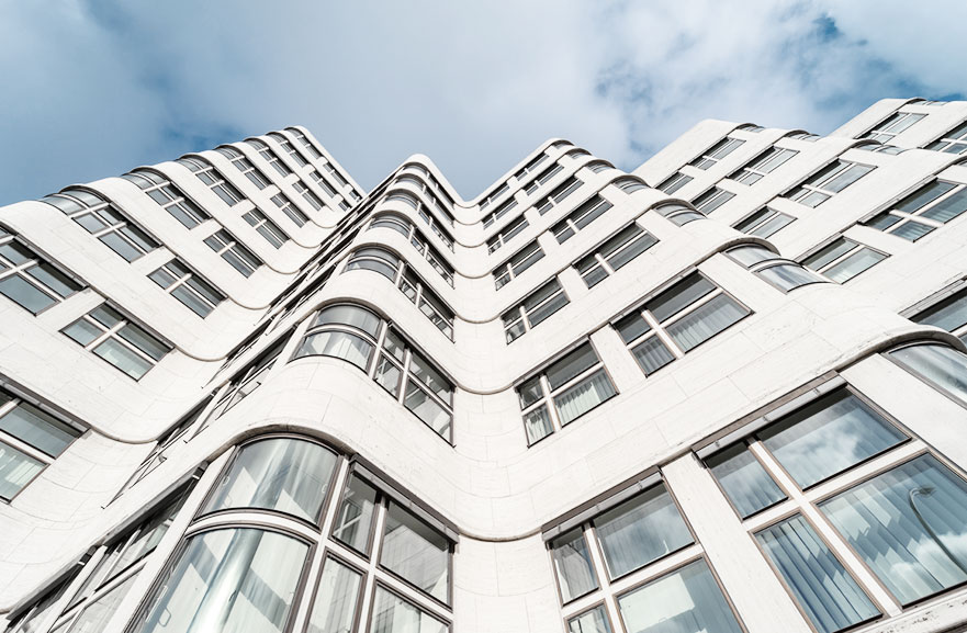 Visão inferior de edifício com estrutura ondulada, com paredes da cor marrom e várias janelas