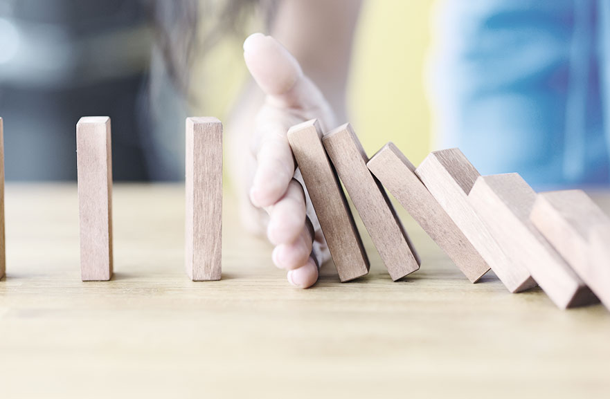 mão segurando blocos de madeira dispostos em sequência, posicionados em cima de mesa