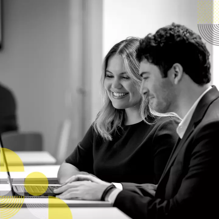 Um homem e uma mulher sorrindo enquanto trabalham em frente a um notebook